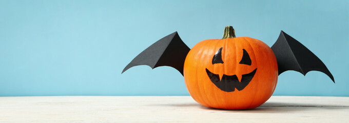 Pumpkin with smile and wings on blue background