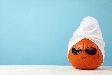Pumpkin with towel and under eye patches against blue background