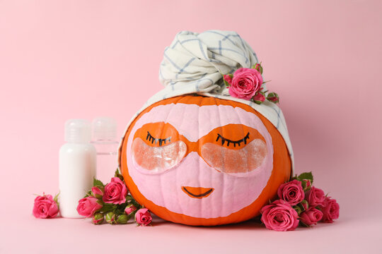 Skincare supplies, pumpkin with eye patches and towel on pink background