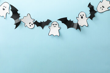 Paper ghosts and bats on blue background, space for text