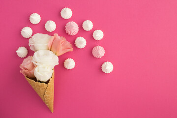Ice cream cone with pink and white flowers and  meringue on the pink background