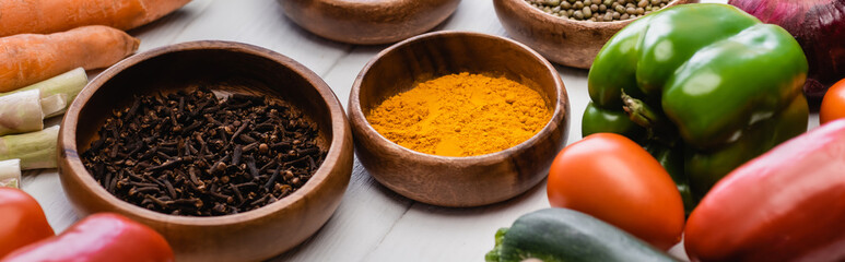 fresh ripe vegetables and fruits around bowls with spices on wooden white background, panoramic shot