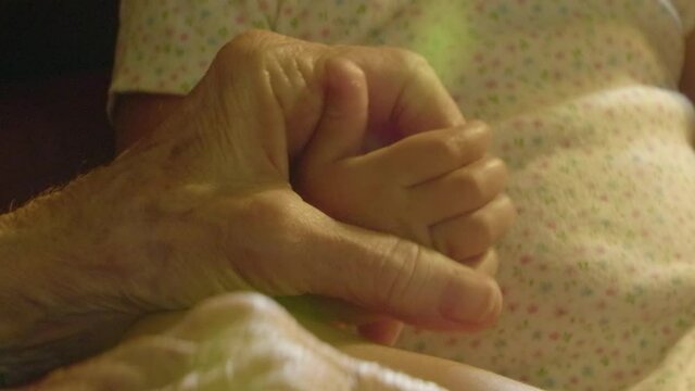 A person rubs the hand of a baby