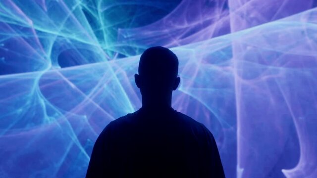 A silhouetted man stands in front of projected lights and animations