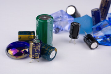 Closeups of capacitors and switches set against a white background with blue marbles and crystals in the foreground.
