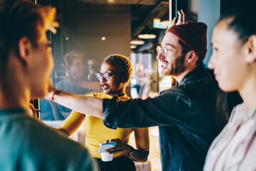 Millennial male and female professionals in trendy wear discussing ideas and solutions making research together, young hipster students communicating while analyzing information in university campus