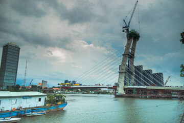 Obraz premium skyline with buildings and Saigon river in sunset, a new cable-stayed bridge is building connecting Thu Thiem peninsula and District 1 across the Saigon River.