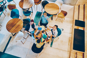 Top view of smiling young multiracial employees enjoying productive job planning startup at round table with laptop computer, from above picture of skilled crew of students training and learning