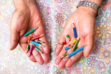 senior man painting with very small coloring pencils due to their use , concept  better use of...