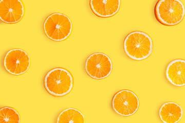 Top view of pattern, laid out slices of juicy oranges on yellow background. Summer tropical citrus fruit for preparing cool freshly squeezed juices, cocktails, drinks, beverages concept.