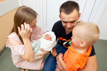 Obraz na płótnie Canvas Family with a newborn baby. Mom dad and son look at the newborn sister.