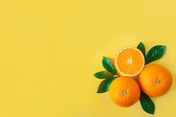 Composition of oranges, slices, pieces, green leaves are laid out on corner of yellow background. Summer tropical exotic citrus fruit for preparing cocktails, beverages, drinks concept.