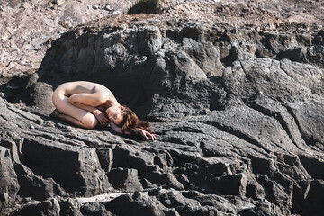 Young nude woman tans on beach