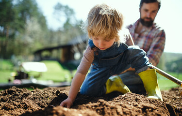 Father with small son working outdoors in garden, sustainable lifestyle concept.