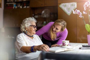 Young woman spending time with her elderly grandmother at home
 - obrazy, fototapety, plakaty