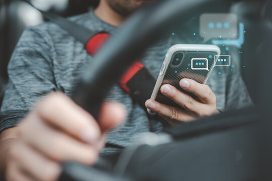 Man Texting while driving car. Irresponsible man Chatting and using smartphone. Writing and typing message with cellphone in vehicle. Holding steering wheel with other hand.