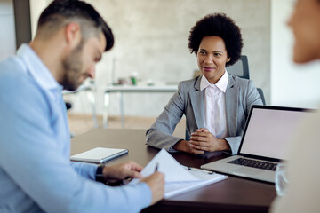 Smiling African American bank manager closing a deal with her clients in the office.