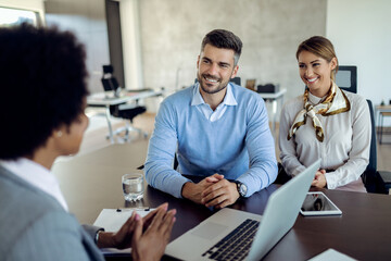 Young happy couple having a meeting with real estate agent in the office.