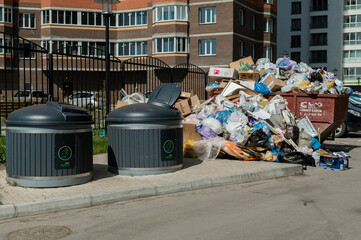 Crowded garbage cans in the courtyard of a residential apartment building. Garbage sorting...