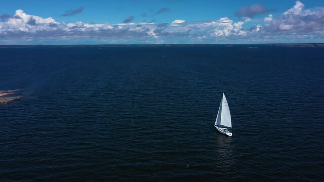Aerial view around a white sail boat on the high seas, peaceful wind at the Finnish Gulf, warm, sunny, summer day, in Uusimaa, Finland - orbit, drone shot