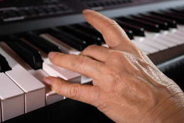 Obraz premium Mature woman learns to play keyboard or piano, woman's hands