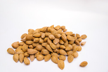 Inshell almonds on a white background. Almonds are arranged in a pile.