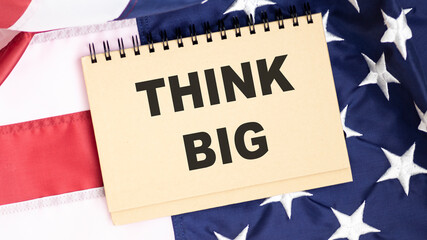 Fototapeta na wymiar Blank notebook with the text THINK BIG on the background of the American flag.