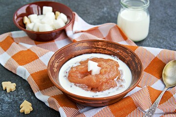 Dessert, thick rhubarb jelly or kissel  in a clay bowl on a dark background. Served with cream.