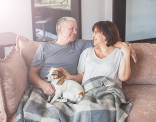 Happy elderly couple sitting on sofa at home