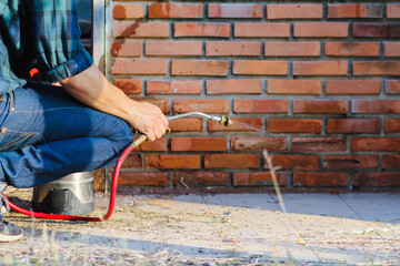 Employees at a termite control company are using a chemical sprayer to get rid of termites at...