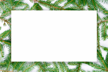 Christmas design template with copy space in the form of a white sheet of paper on the background of real fir branches. Minimal design for Christmas greeting cards, invitations, social media post
