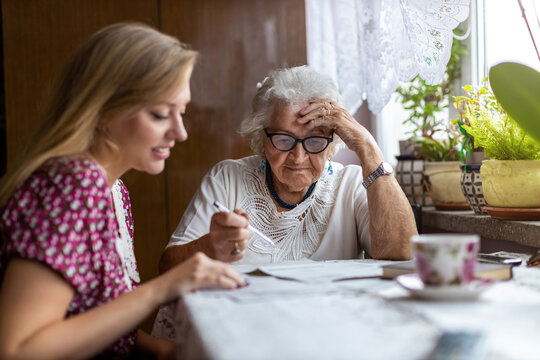 Young woman helping elderly grandmother with paperwork
