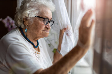 Senior woman looking out of window at home
