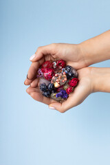 Hands holding fruit ice cubes, organic berries and dried flowers. Minimal summer concept. Top aerial view.