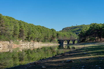 Fototapeta na wymiar Reservoir landscape with nice reflections of the forest in the water on a day with blue sky