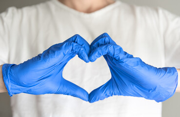 Hands show heart gesture with protective gloves.