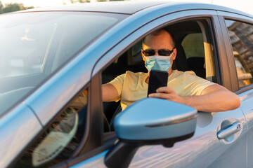 male driver wearing face protective medical mask using smartphone