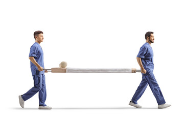 Full length profile shot of two male healthcare workers carrying an empty stretcher