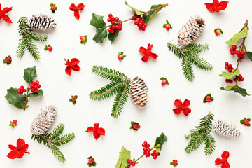 Christmas background with pine cones, branches of holly with red berries and fir tree on white....