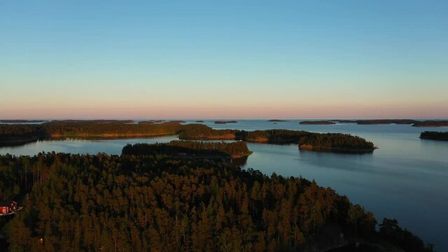 Aerial view over islands, in the Swedish archipelago, during a colorful, summer sunset, at the Gulf of Bothnia, in Sweden - rising, drone shot