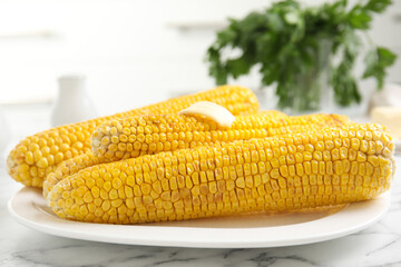Fresh grilled corn cobs with butter on white marble table, closeup