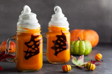 Halloween Pumpkin  cocktail with whipped cream in ghost shape and chocolate spider web. Freakshake for party.