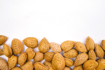 Inshell almonds on a white background. Almonds are arranged in a pile.
