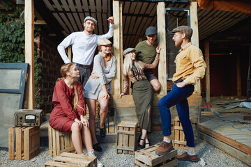 Group of young caucasian people, three girls and three men.They are siting on wooden box .