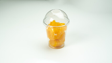 pieces of tangerine in a plastic cup on a white background