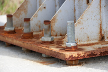Rusty bolts and nuts securing the metal base of the mast to the concrete