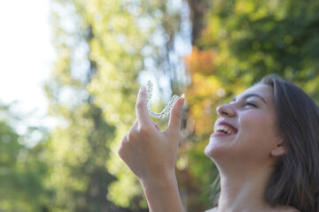 Beautiful smiling Turkish woman is holding an invisalign bracer