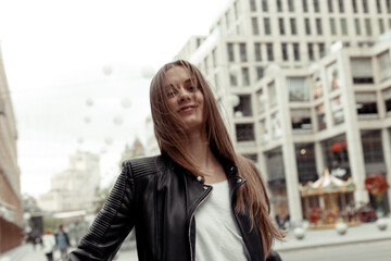 Fototapeta na wymiar Smiling blonde girl with windy hair. Woman wearing black eco-leather jacket