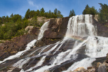 Obraz premium Beautiful Furebergsfossen waterfall in Norway, waterfall on rocky slope near road along the Hardangerfjord fiord