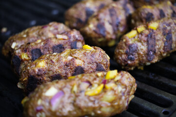 Macro closeup of grill with isolated cevapcici meat balls on cooking grid (selective focus on central ball left)